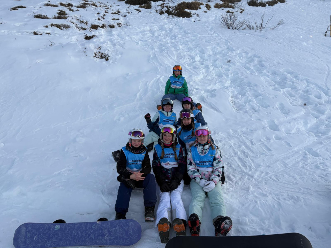Snowboardkurs sitzend im Schnee